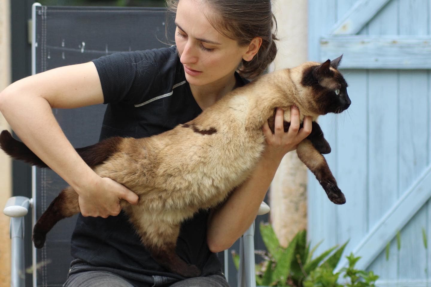 Marie Salabert porte un chat siamois contre elle avant une séance.
