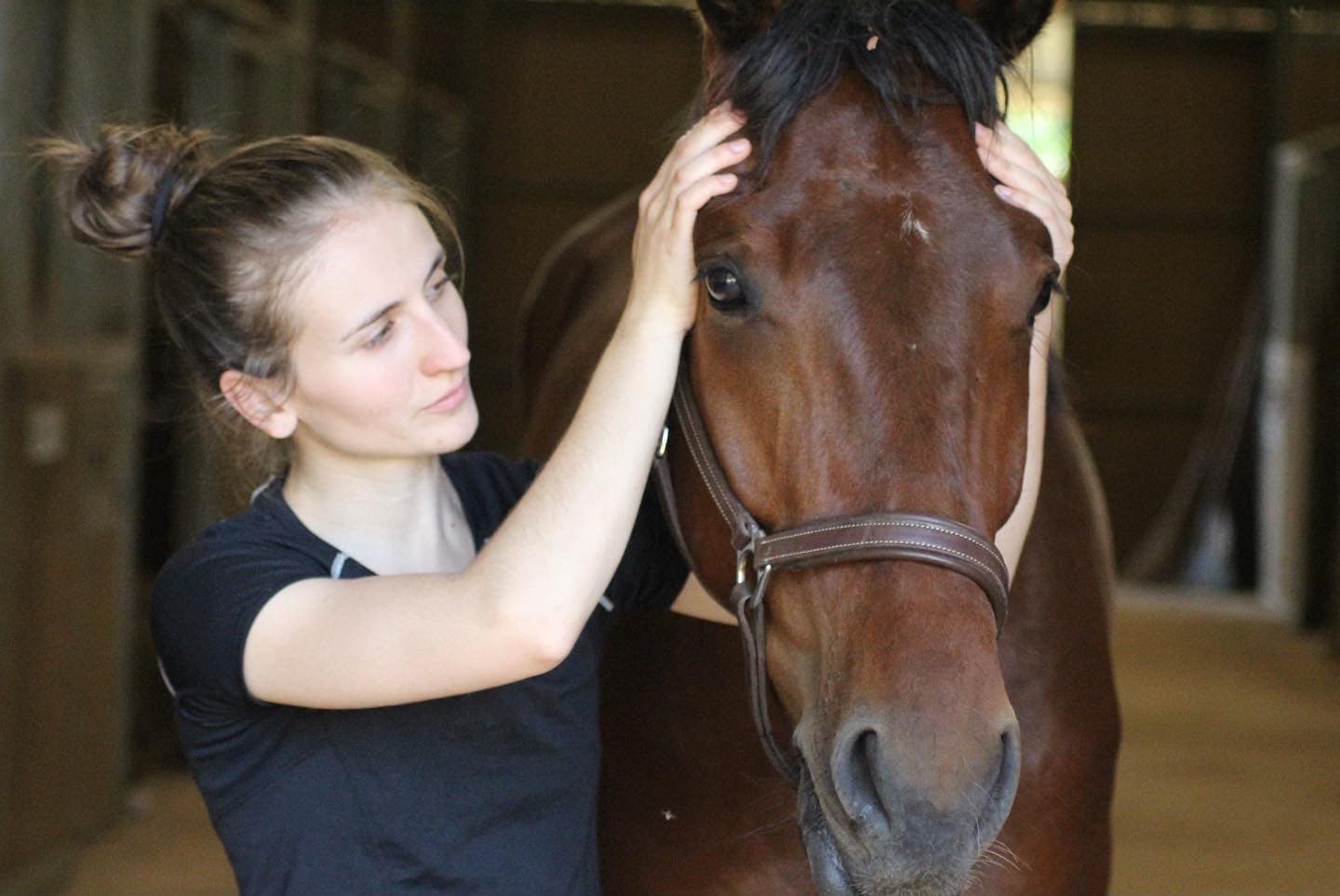 Marie Salabert mobilisant le postérieur d'un cheval en écurie