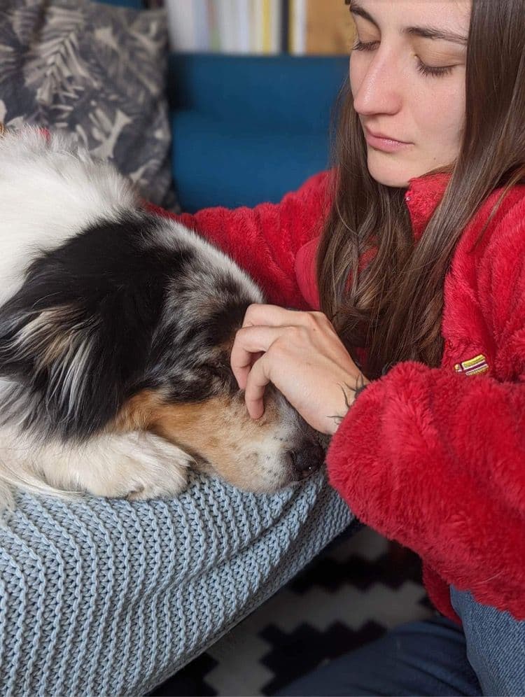 Marie Salabert pose les mains sur la tête d'un berger australien