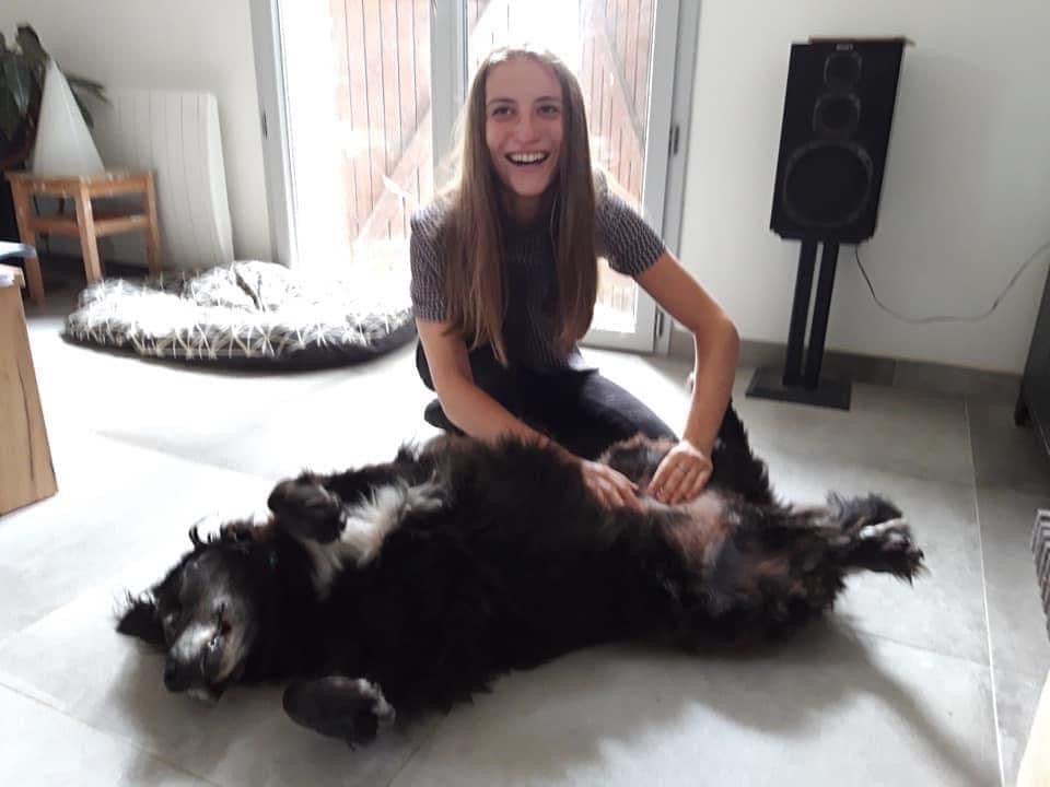 Marie Salabert, souriante, avec un chien noir allongé sur le dos